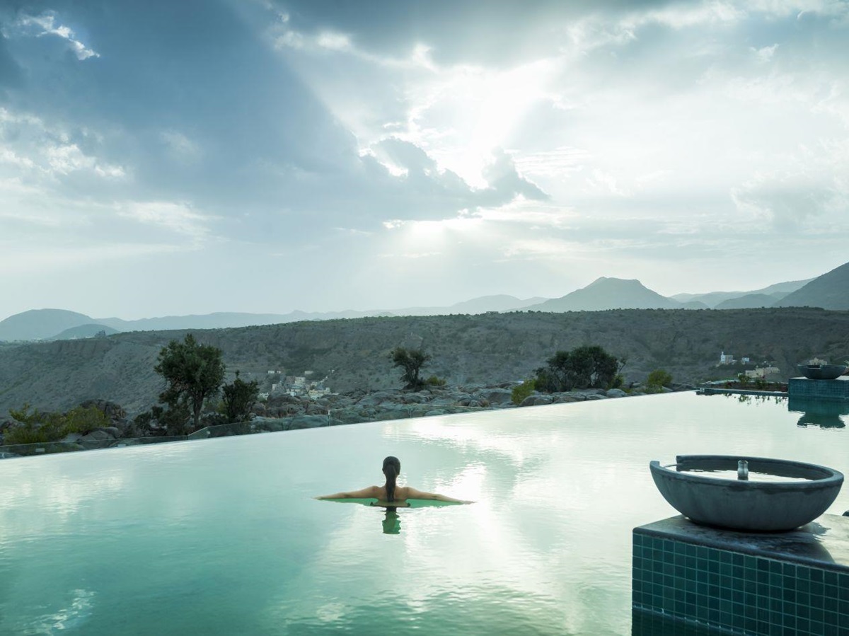 A lady in the infinity pool looking at the view of the mountains at the Anantara Al Jabal Al Akhdar Resort in Oman