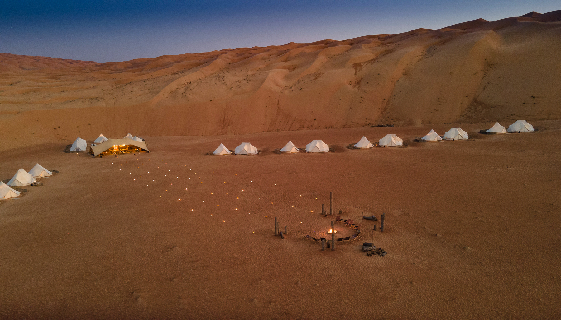 Exterior view of tents and firepit at Magic Camps Wahiba Sands in the Sharqiya Sands in Oman