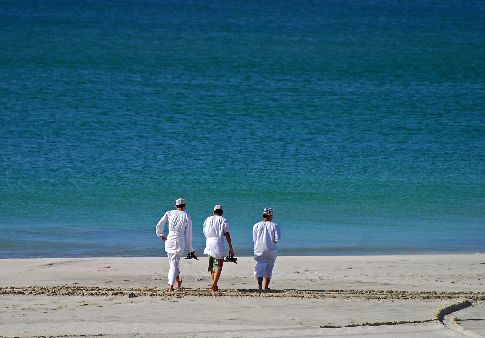 Local men walking along a beach in Oman