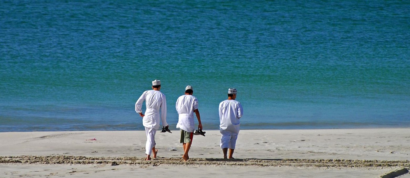 Local men walking along a beach in Oman