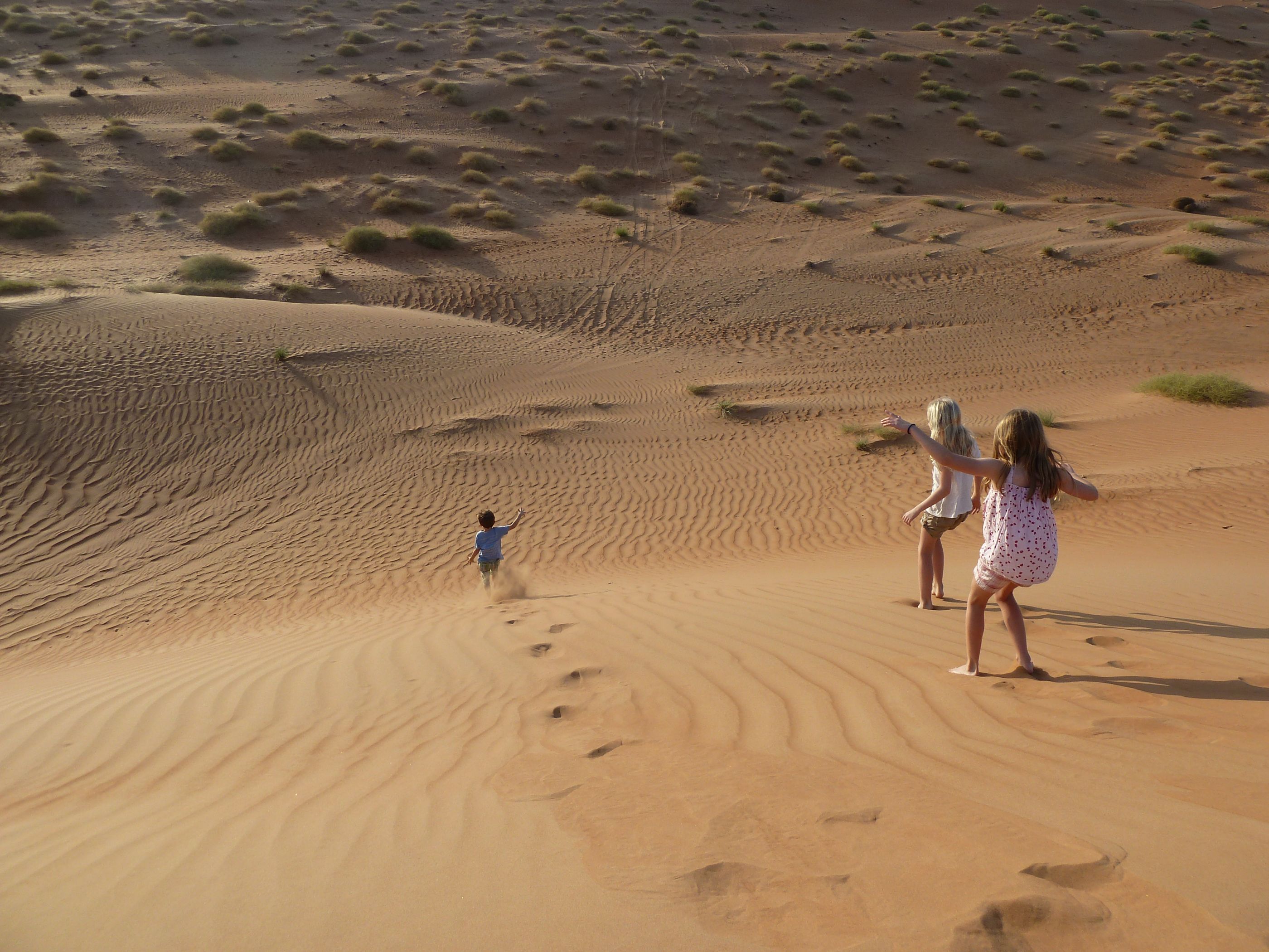 Children running down the dunes in Oman