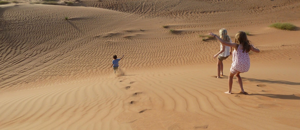 Children running down the dunes in Oman