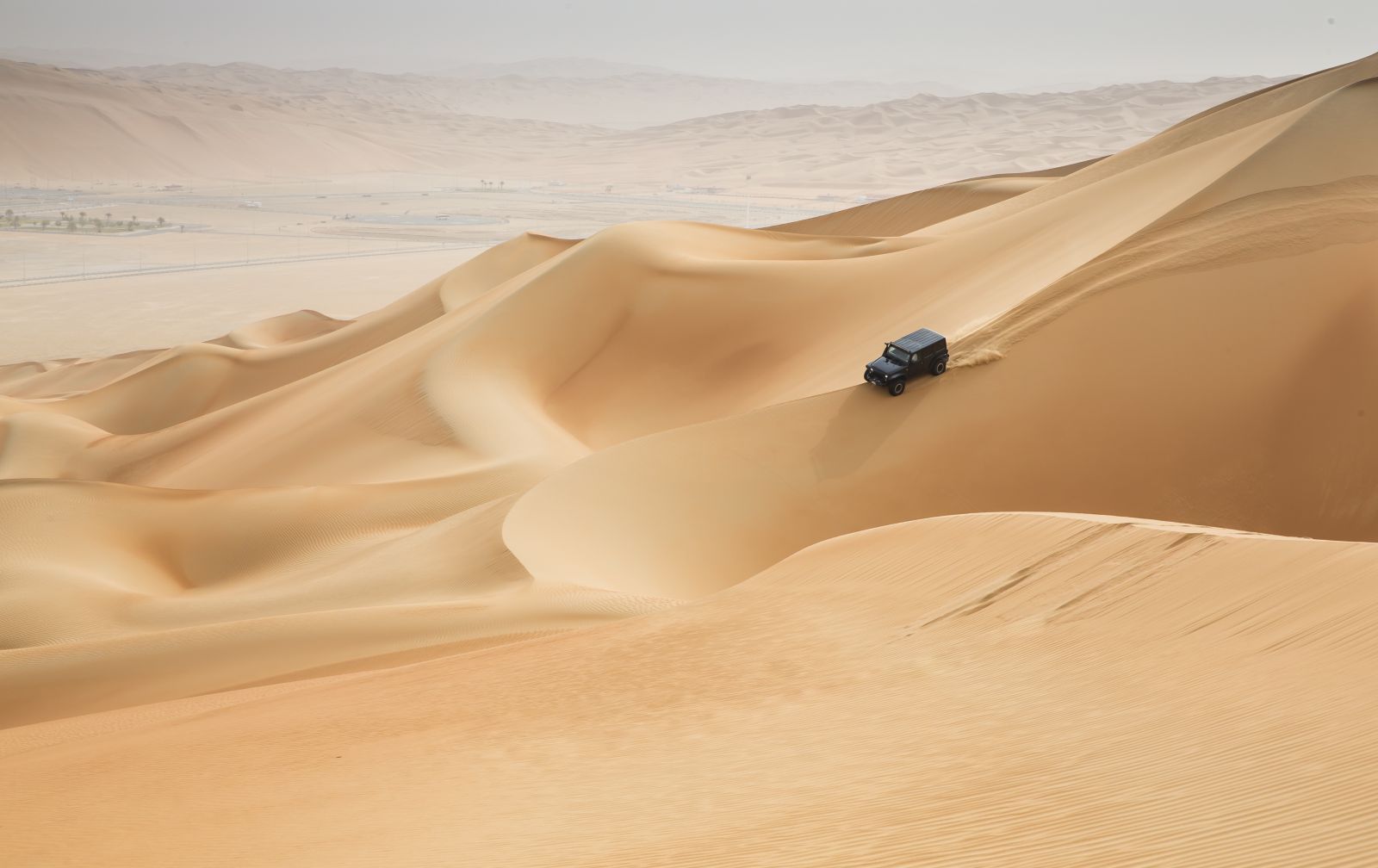 A jeep driving through the desert dunes in Oman