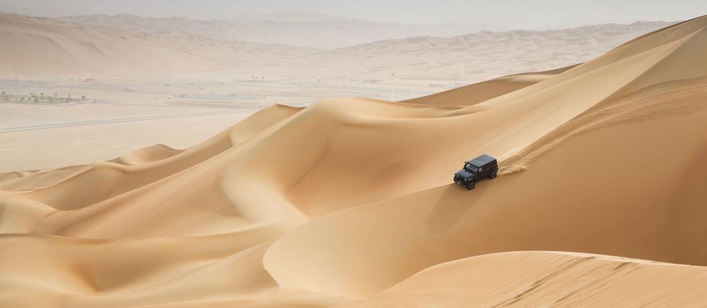 A jeep driving through the desert dunes in Oman