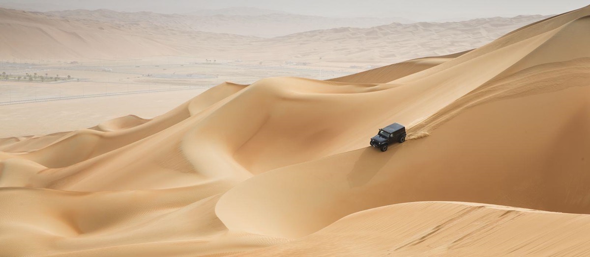A jeep driving through the desert dunes in Oman