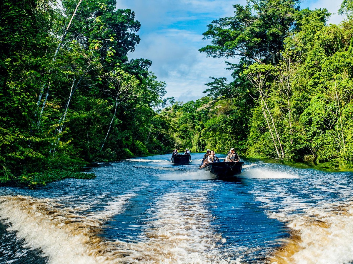 Skiffs sailing across a canal from the Aria Amazon luxury river cruiser in Peru