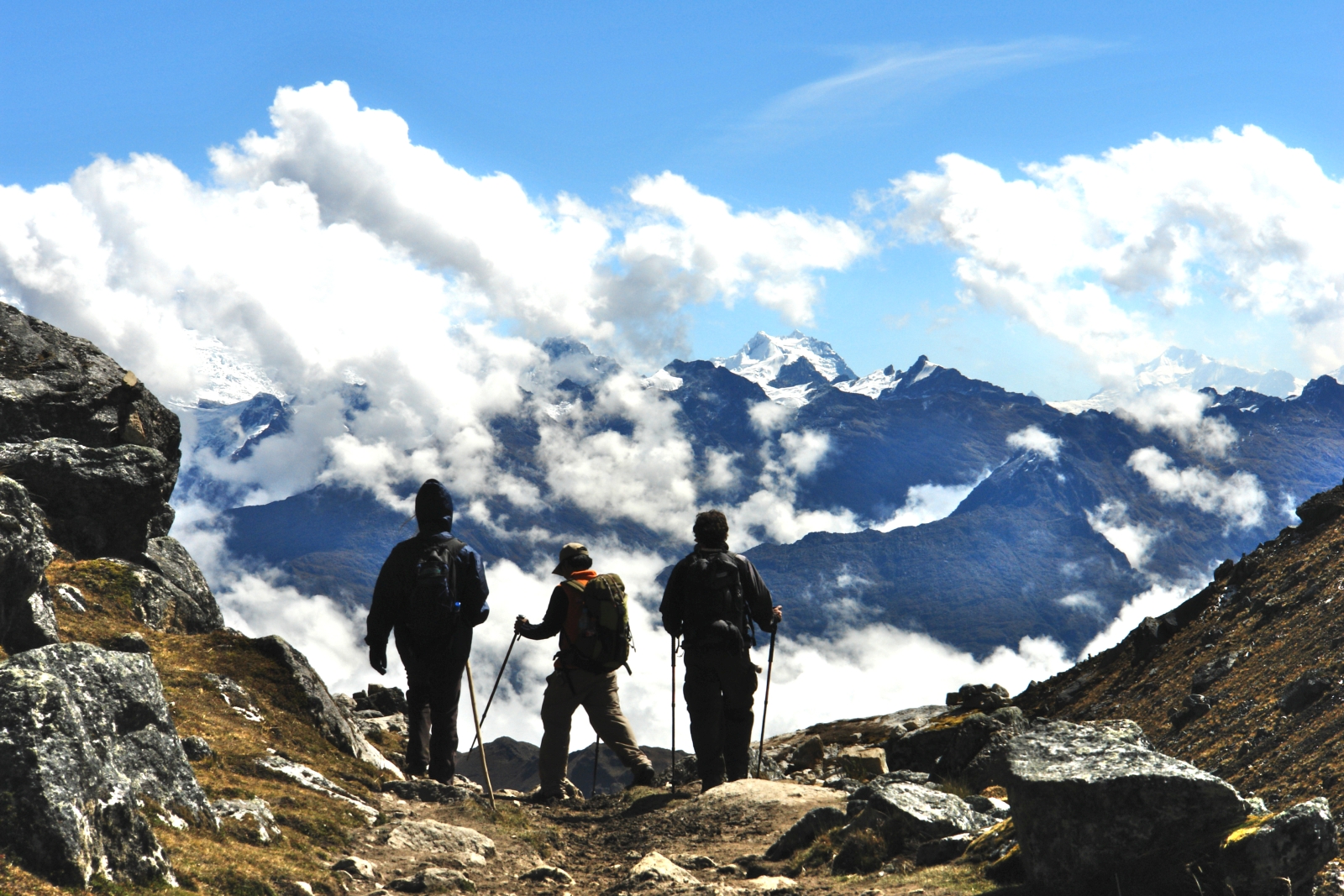 Three hikers looking over the mountains in Peru in the clouds