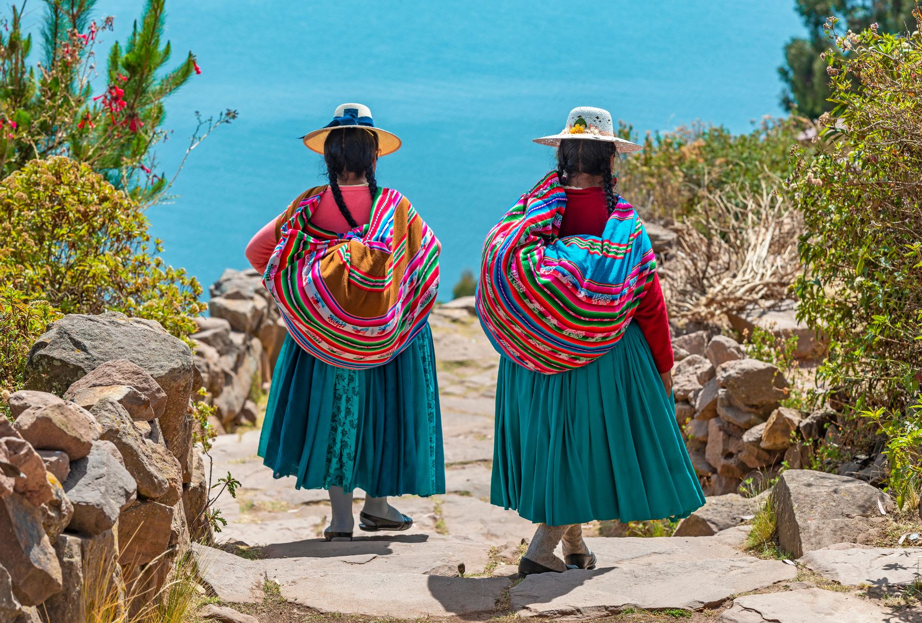 Ladies in traditional dress walking along a path in Taquile island, Peru