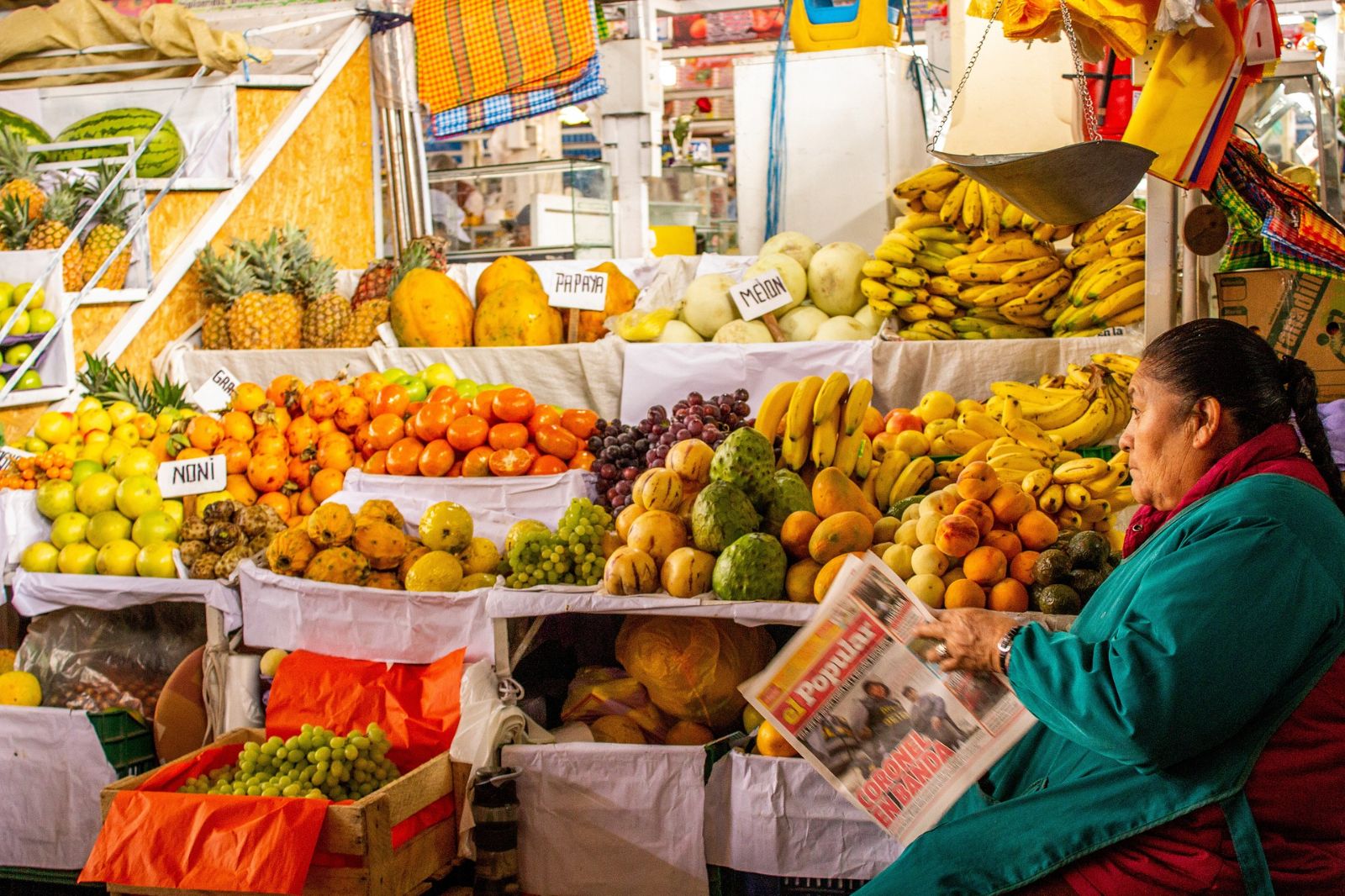 A woman selling vegetables and fruit at a Peruvian market