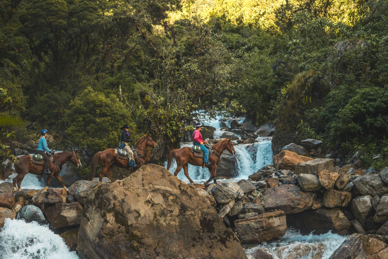 Three riders passing a waterfall