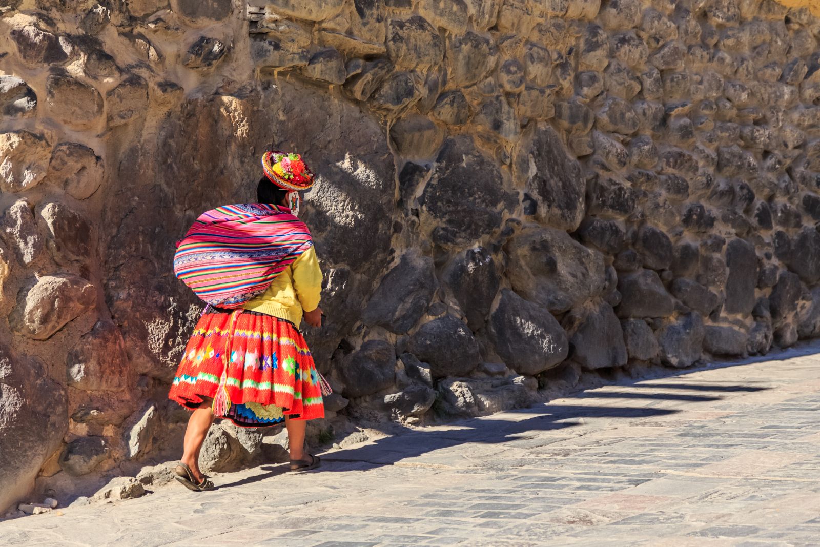 Lady in traditional dress ascending a street in the Sacred Valley of the Incas in Peru