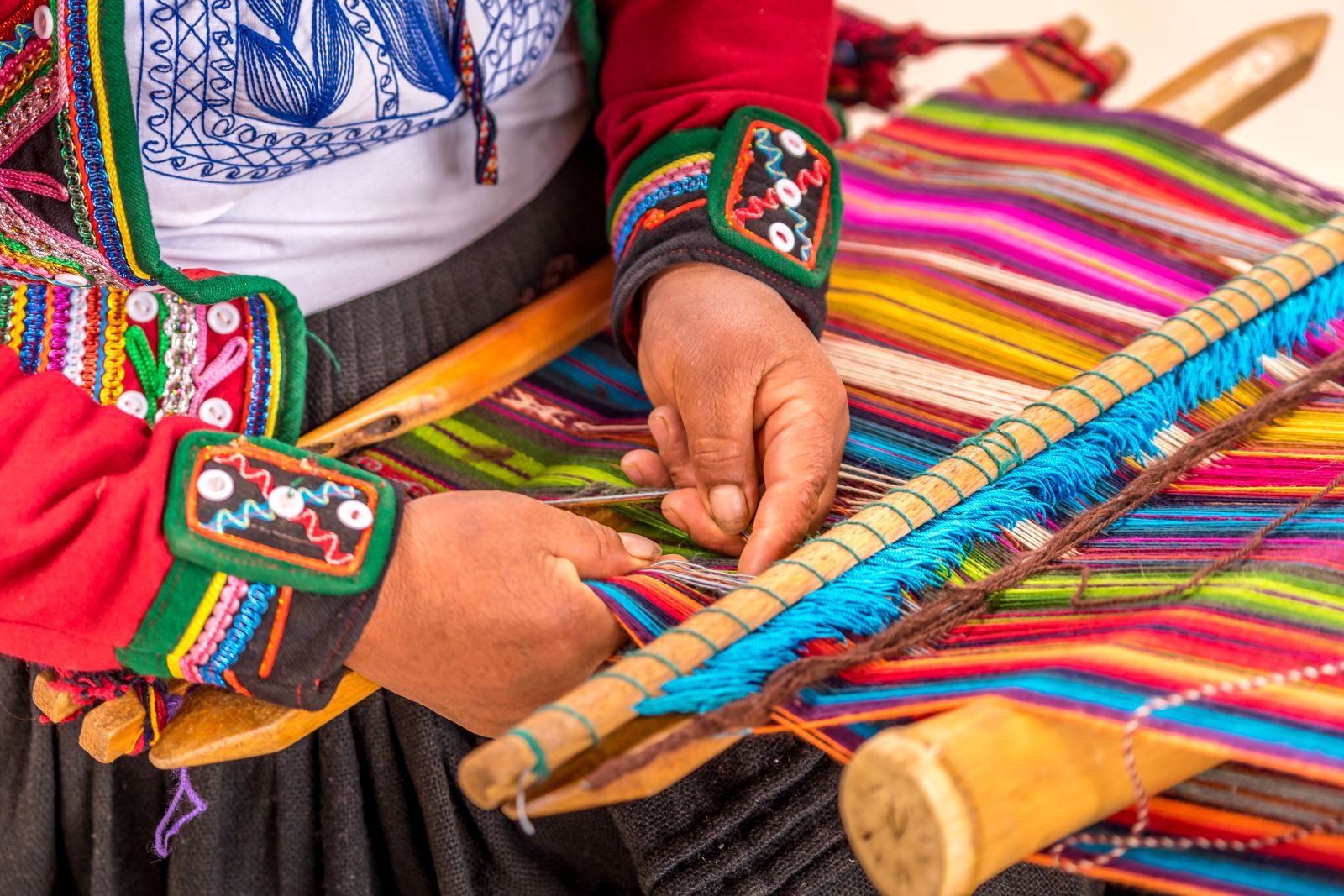 Peruvian lady in traditional dress weaving colourful textiles in the Sacred Valley of the Incas