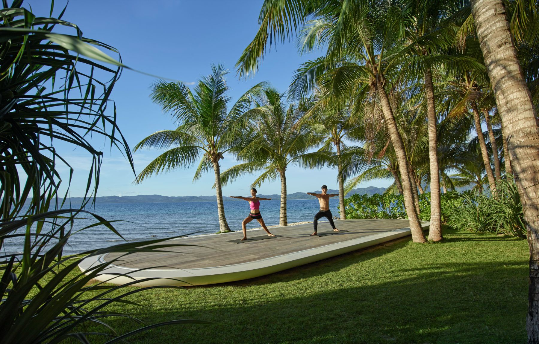 Couple practising yoga by the beach at Banwa Private Island, Philippines
