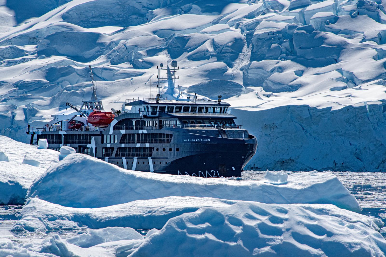 The Magellan Explorer sailing past icebergs in Antarctica