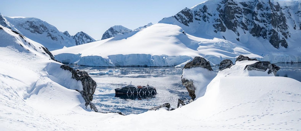 Distant view of the Magellan Explorer in Antarctica surrounded by snowy landscapes
