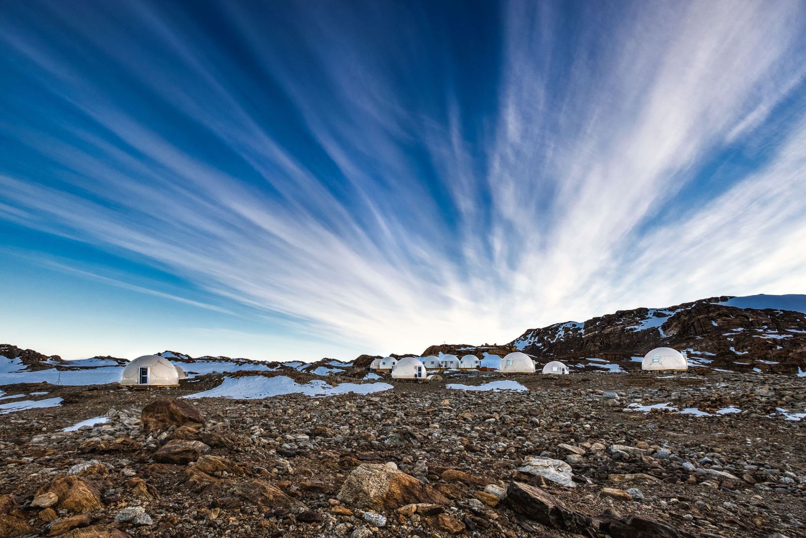 The camp pods sitting in a rocky landscape with a blue sky behind