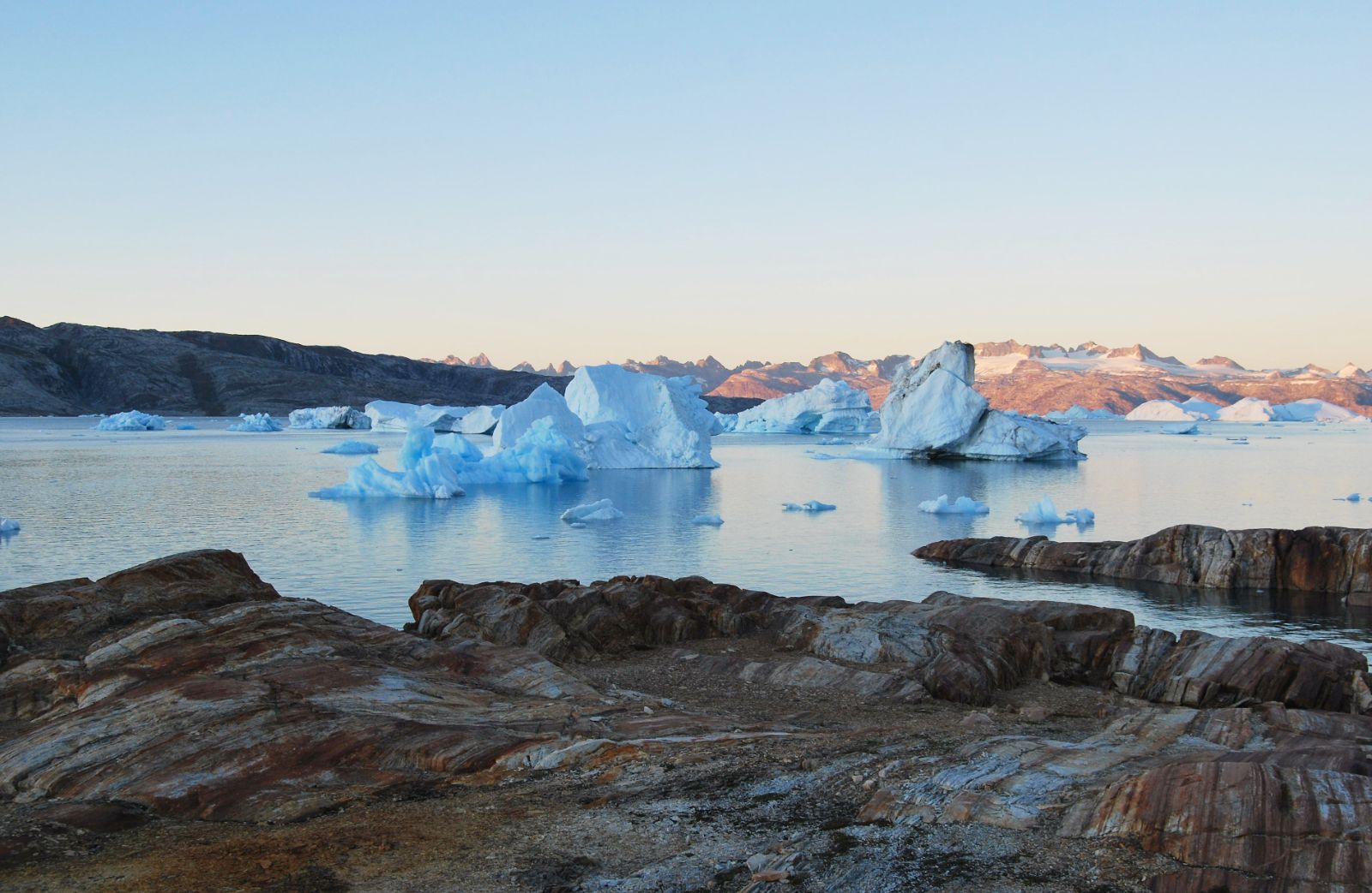 Rocky landscapes in Greenland with a view of a fjord and large icebergs