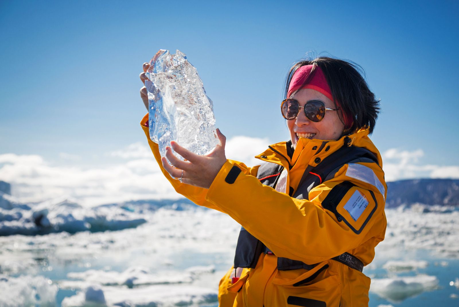 Guest of a Quark Arctic cruise holding a large block of ice in Svalbard, Norway