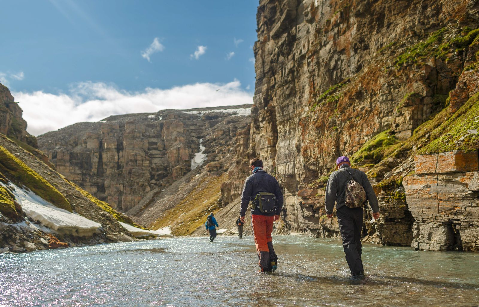 Hikers walking through a shallow valley stream on Somerset Island, Canada