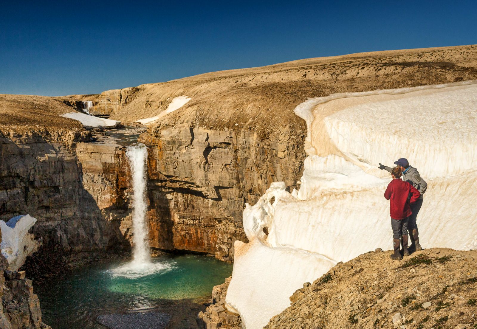 Couple admiring view of glacier and waterfall on Somerset Island in Canada