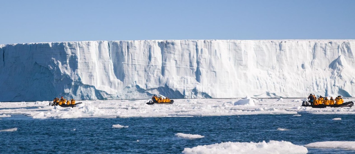 Three Zodiacs at the face of an enormous tabular iceberg in Svalbard, Norway