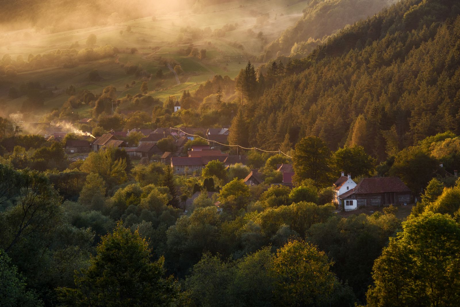 View of a village and misty, forested valley in Transylvania, Romania