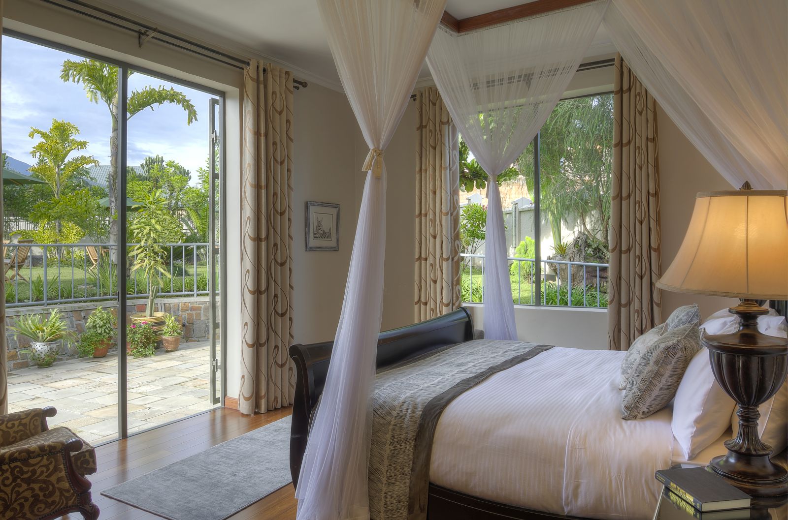 A double bedroom with doors out onto a patio area at The Bishops House hotel in Rwanda 