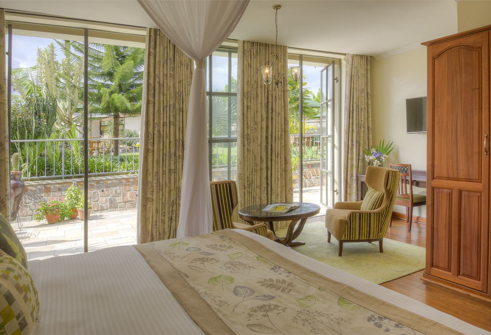 A double bedroom with living area that leads on to an outside patio area at The Bishops House hotel in Rwanda 