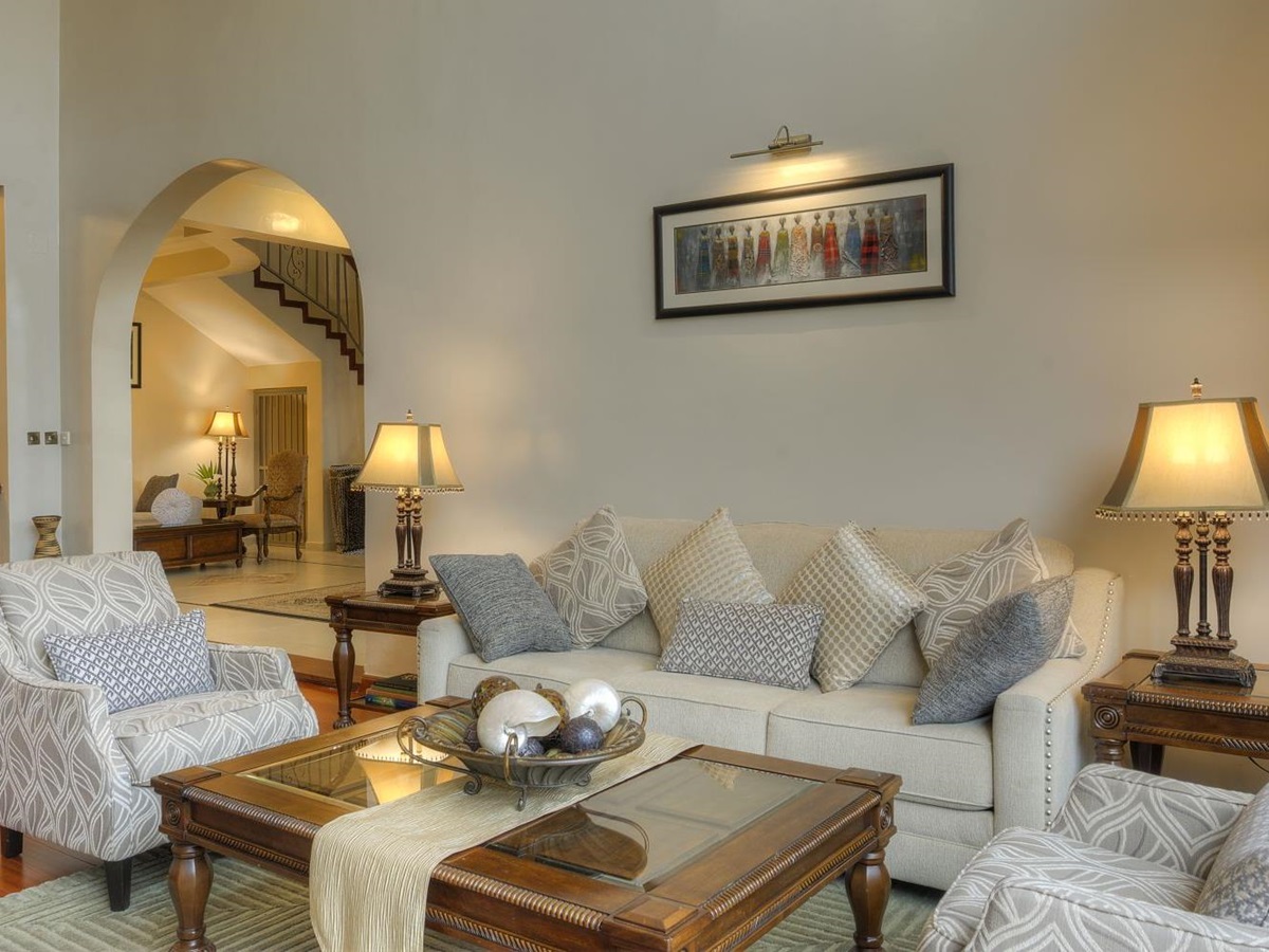 The sitting room The Bishops House hotel in Rwanda with a cream coloured sofa two occasional chairs and a coffee table in the centre