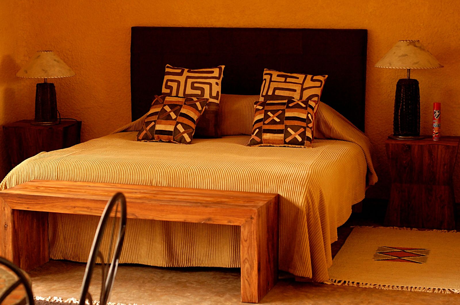 A double bedroom with gold coloured linen and wood furniture at Sabyinyo Silverback Lodge in Rwanda