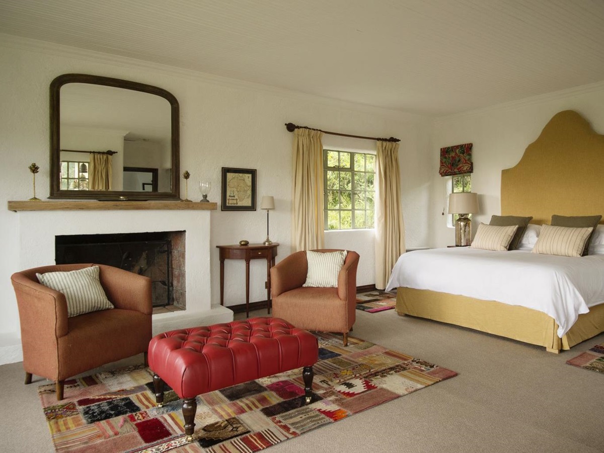 A double bedroom suite with a fireplace, chairs and table at Sabyinyo Silverback Lodge in Rwanda