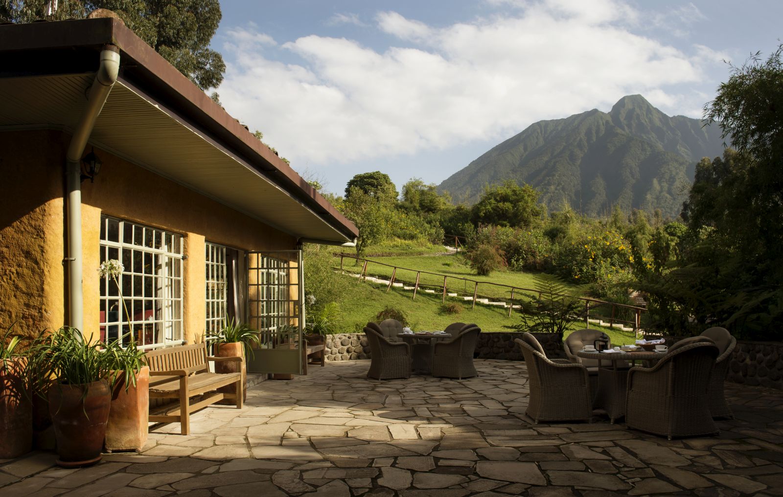 The outside patio with wicker furniture at Sabyinyo Silverback Lodge in Rwanda with a view of the mountains in the background