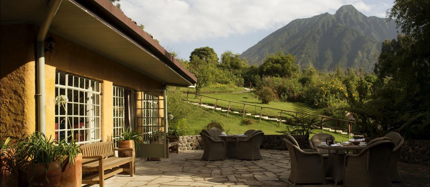 The outside patio with wicker furniture at Sabyinyo Silverback Lodge in Rwanda with a view of the mountains in the background