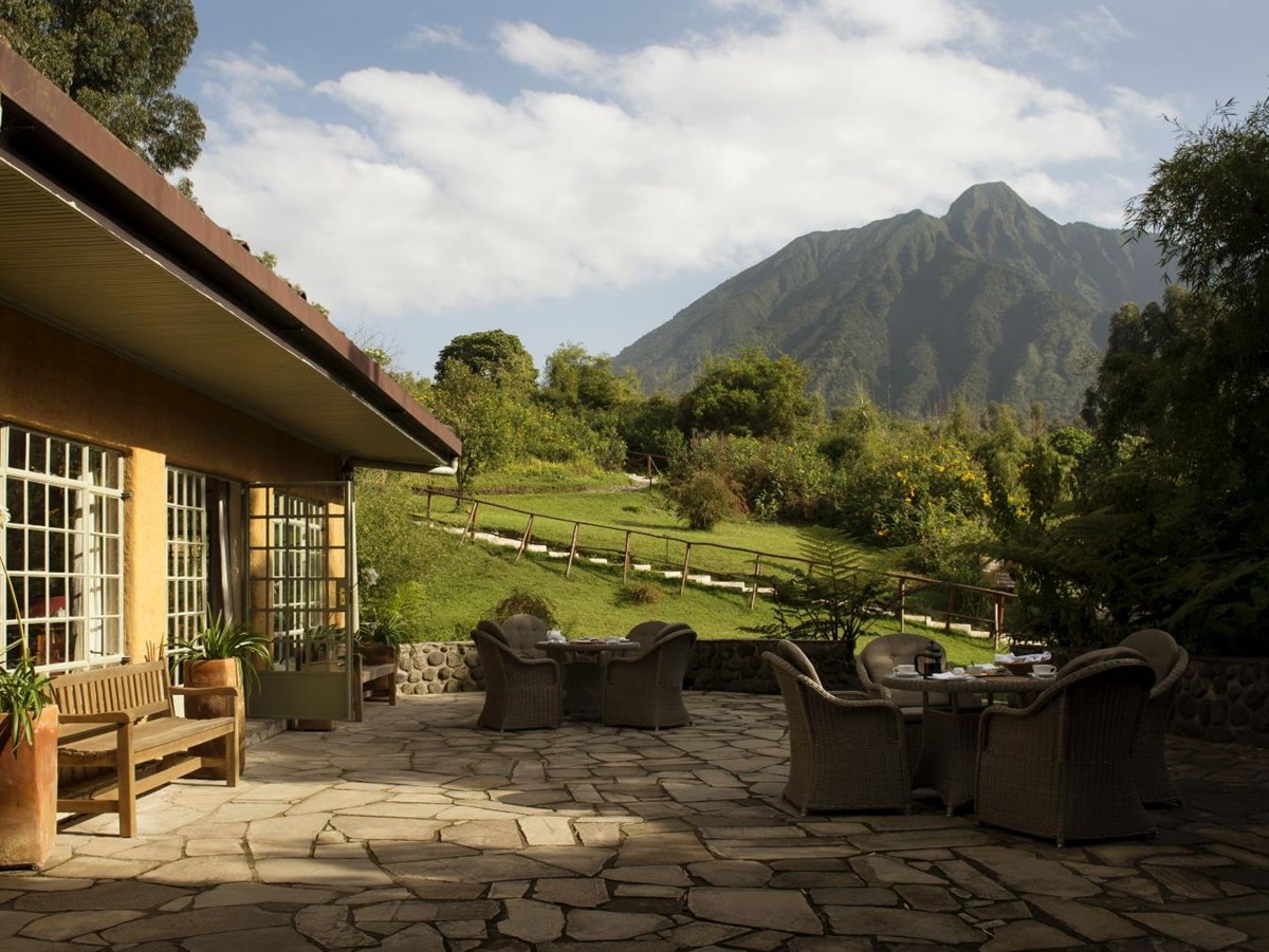 The outside patio with wicker furniture at Sabyinyo Silverback Lodge in Rwanda with a view of the mountains in the background