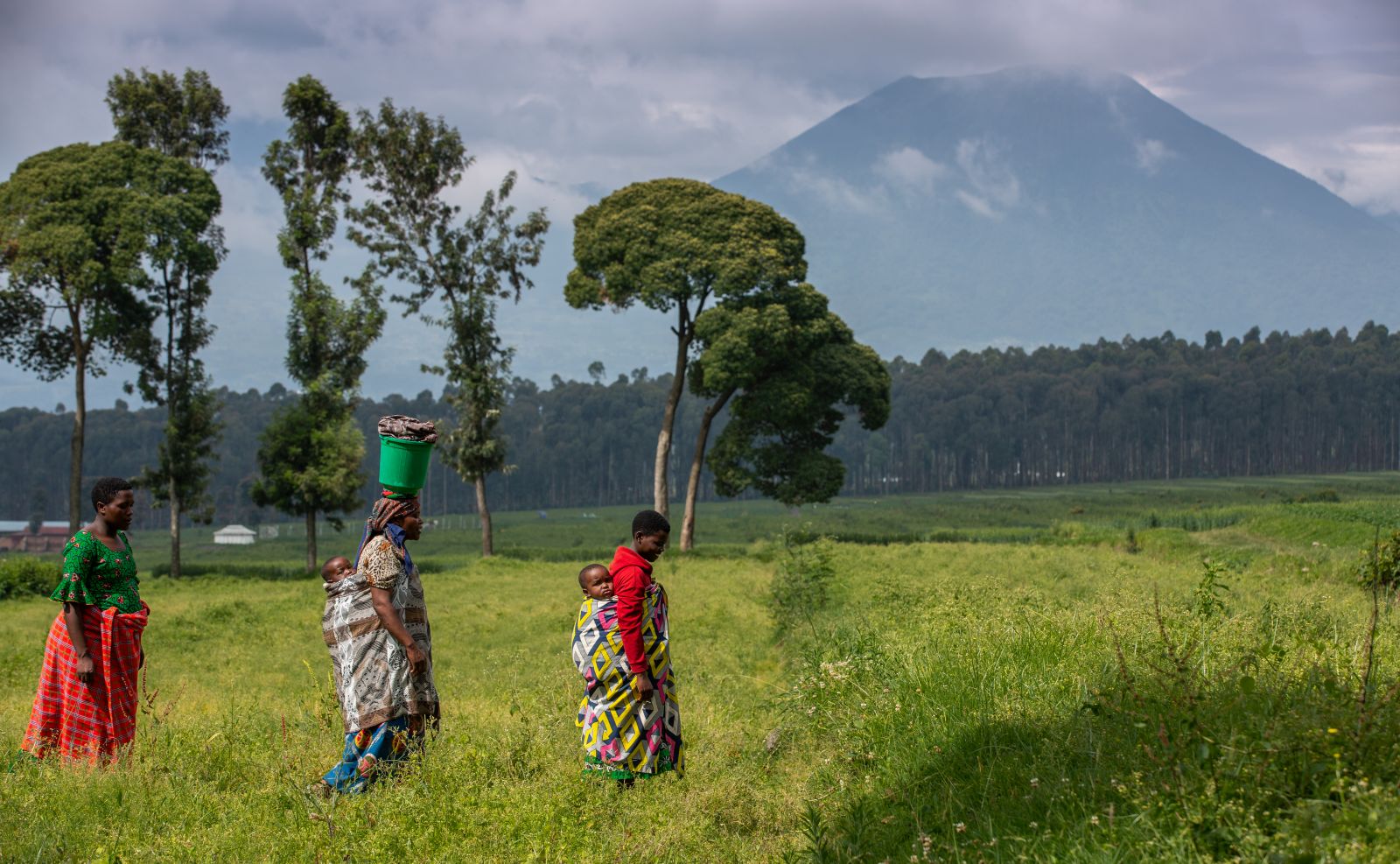 People walking past a volcano at Singita Kwitonda Lodge in Rwanda