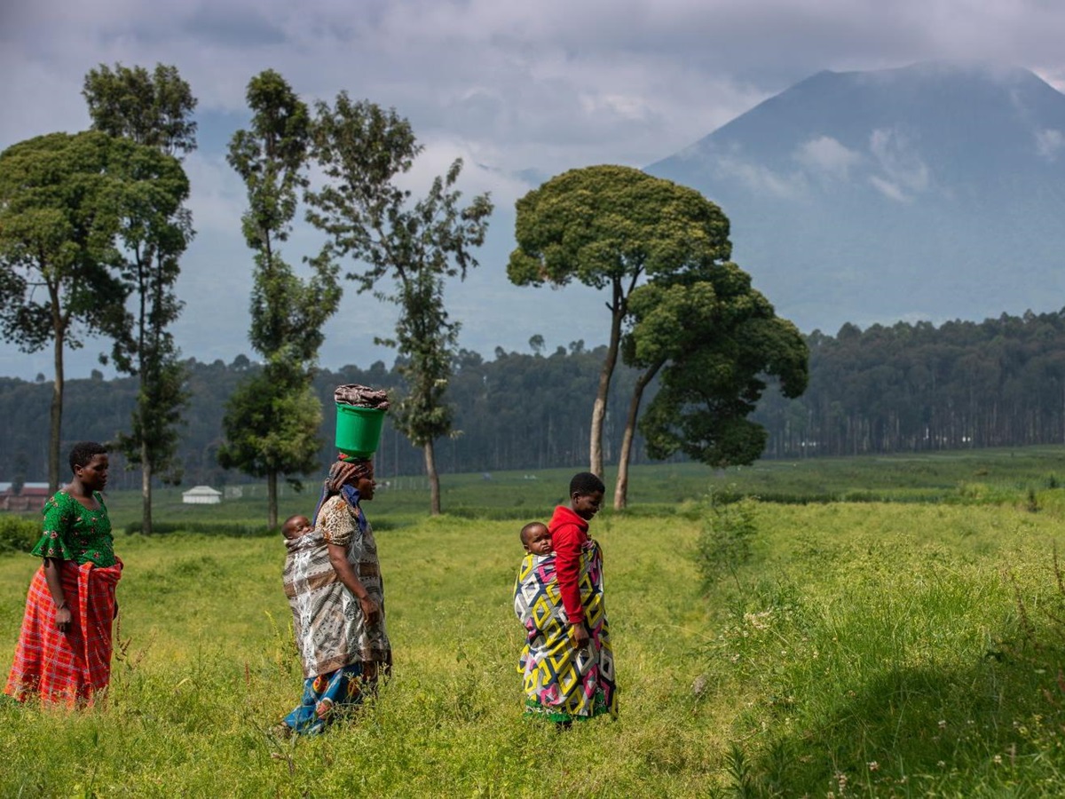 People walking past a volcano at Singita Kwitonda Lodge in Rwanda