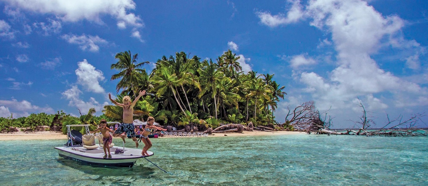 kids jumping of a boat at alphone island, seychelles