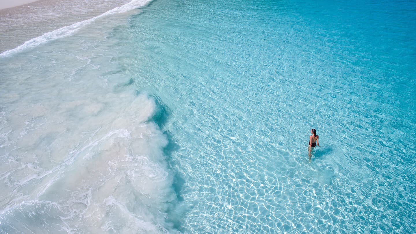 person walking in water at Constance Lemuria, Seychelles