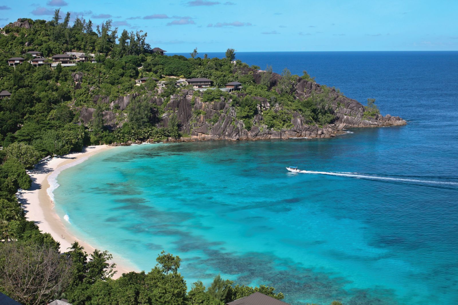 A boat cruising along the beach at Four Seasons Seychelles