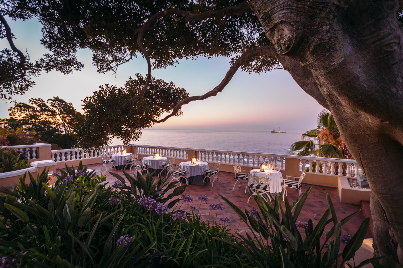 Sunset dining on the terrace of luxury hotel Ellerman House in Cape Town overlooking the sea