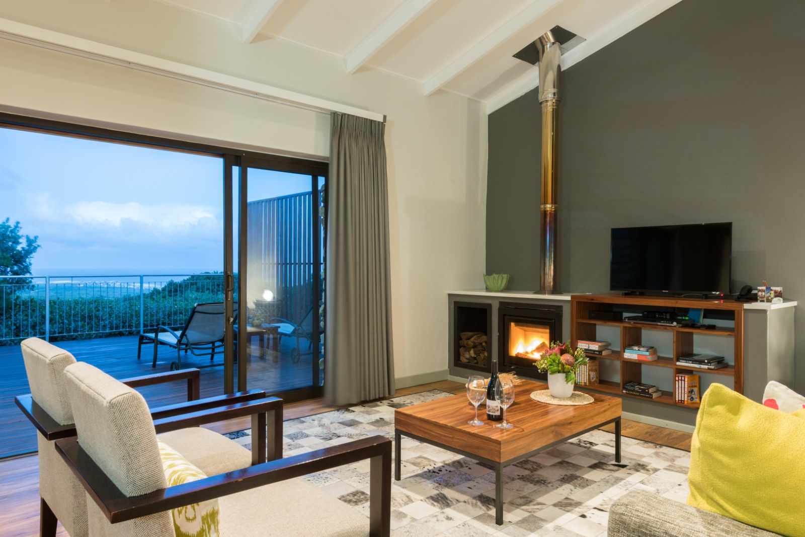 Garden lodge living area with indoor fireplace and sliding doors out onto private terrace at luxury lodge Grootbos Garden Lodge in South Africa
