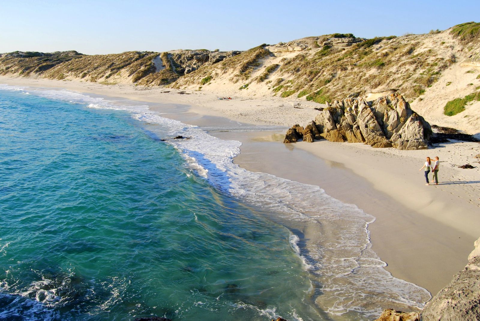 Couple walking along the white sand beach at Grootbos in South Africa