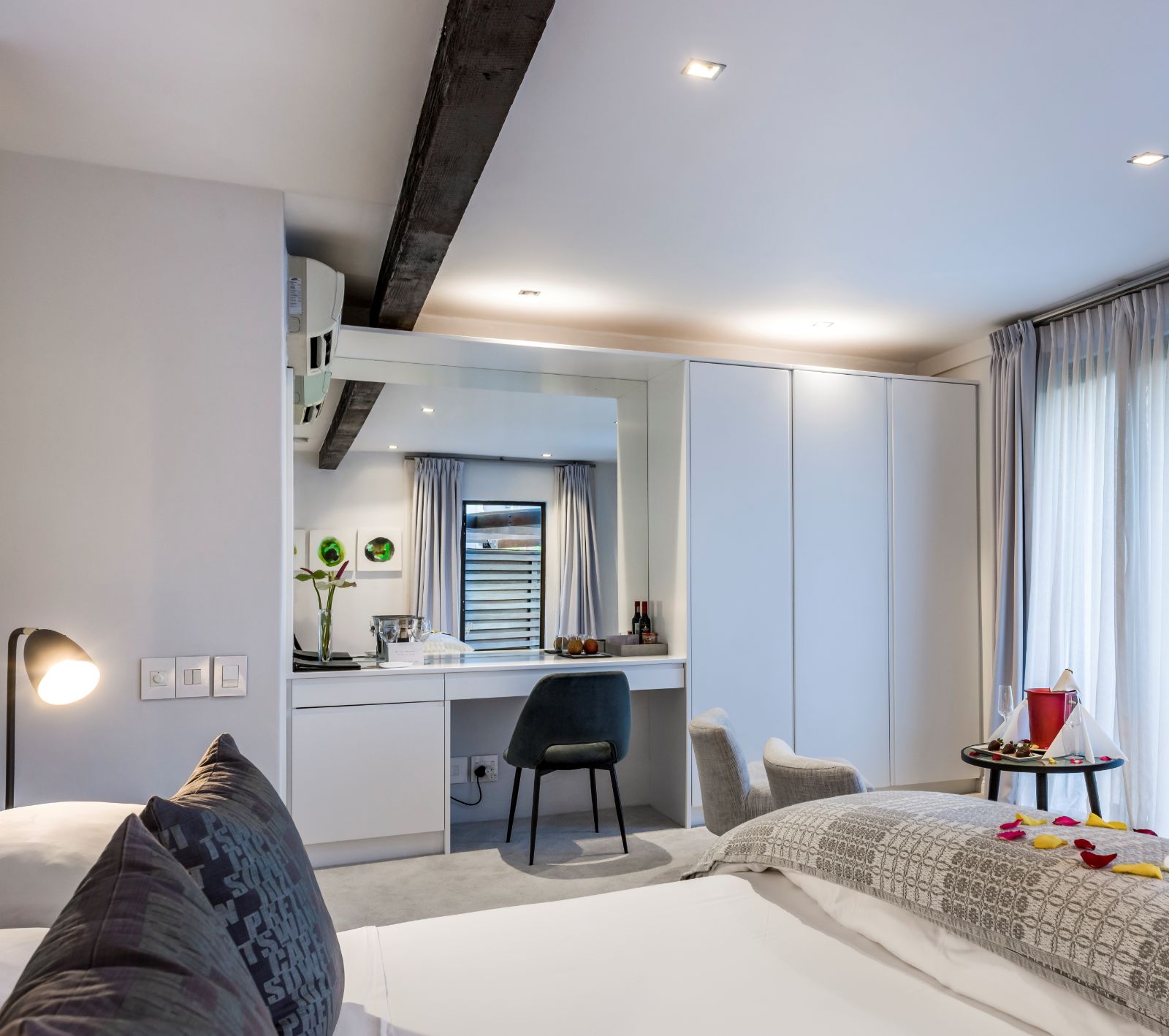 Clean crisp superior room with flower petals and lounge area with balcony at luxury hotel Kensington Place in Cape Town South Africa