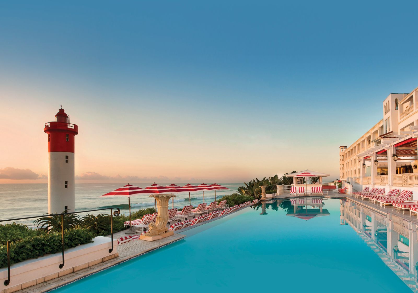 View of The Oyster Box Hotel and its pool by the iconic Umhlanga lighthouse and beach in South Africa