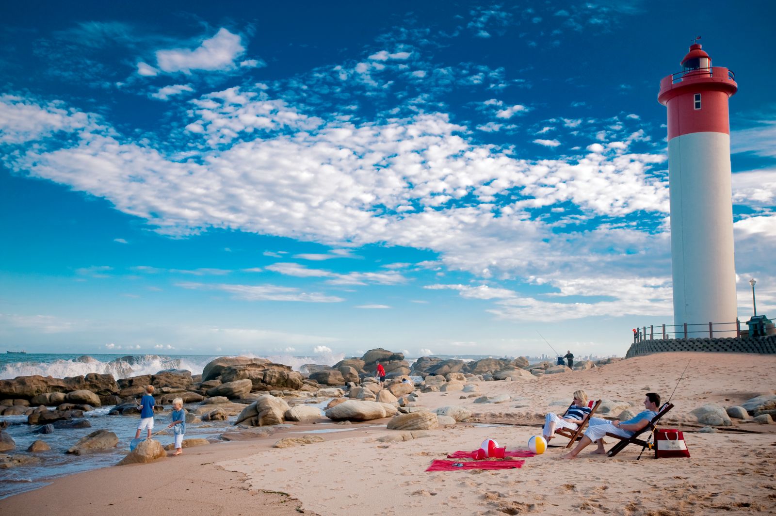 A family relaxing on the beach at Umhlanga lighthouse during a stay at The Oyster Box Hotel