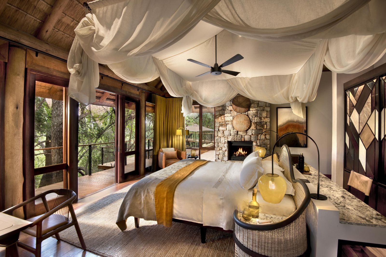 Spacious double bedroom with fan and fireplace at luxury private house Morukuru River House in the Madikwe Game Reserve in South Africa