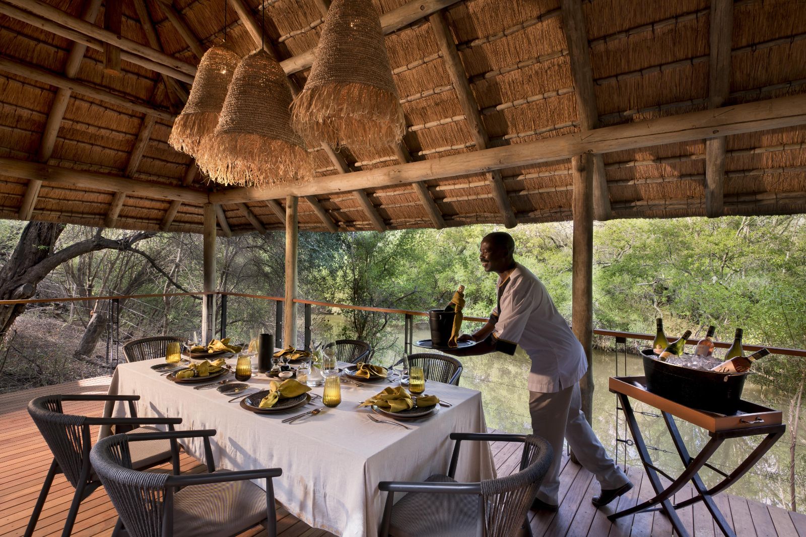 Waiter preparing the river-side dining area at luxury private house Morukuru River House in the Madikwe Game Reserve in South Africa