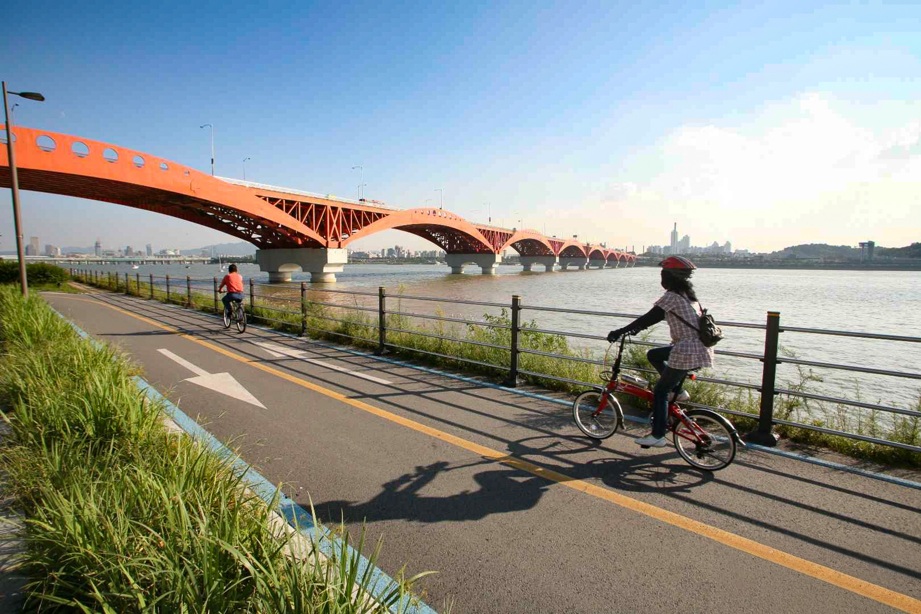 People e-biking under a bridge in Seoul