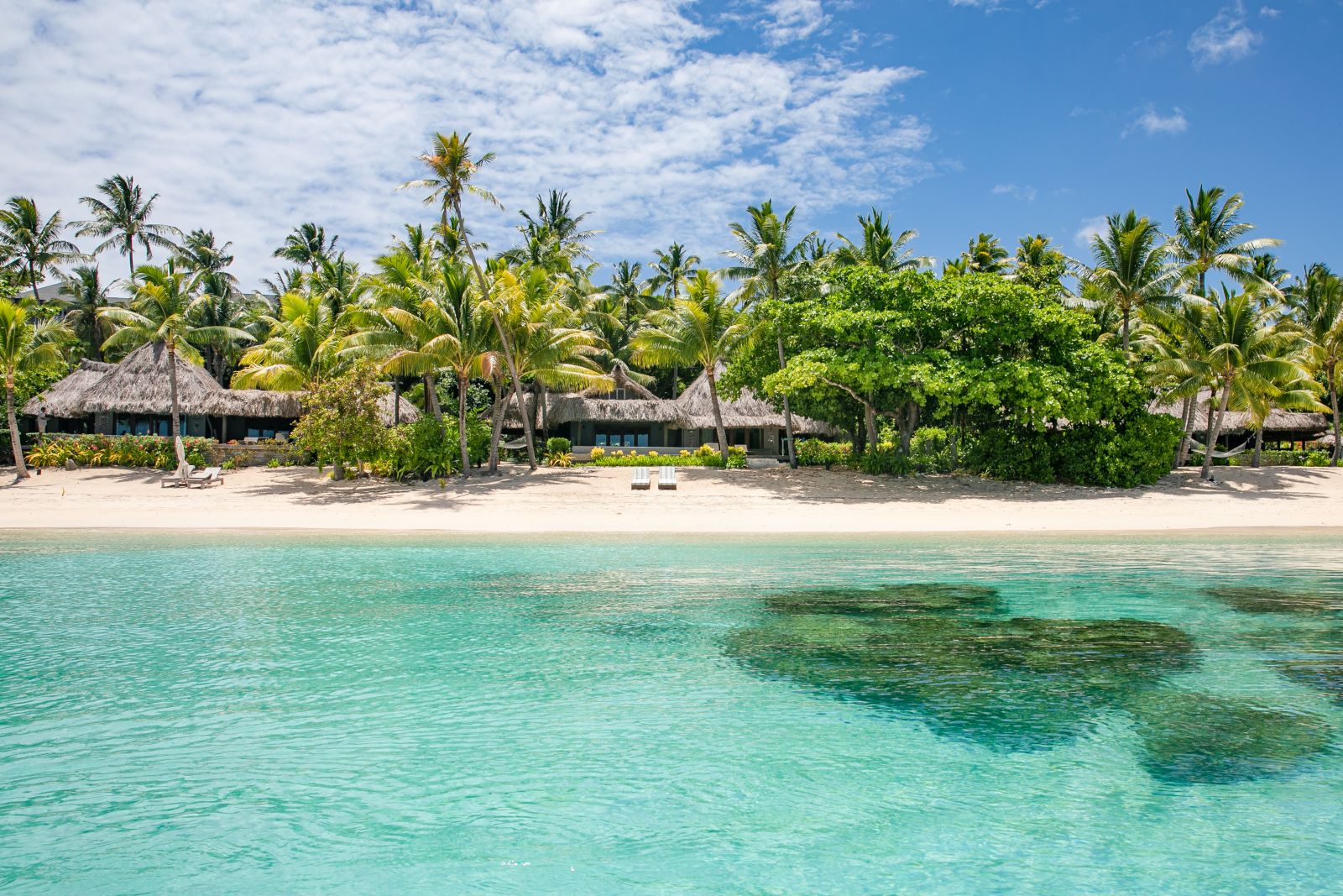 Exterior view of a sunset villa on the sand beach at luxury resort Kokomo Island in Fiji