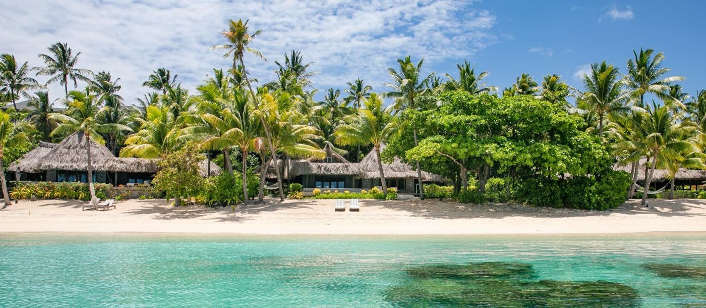 Exterior view of a sunset villa on the sand beach at luxury resort Kokomo Island in Fiji